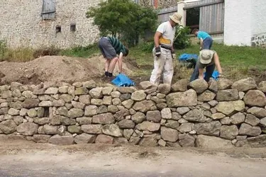 Les volontaires autour du mur en pierres